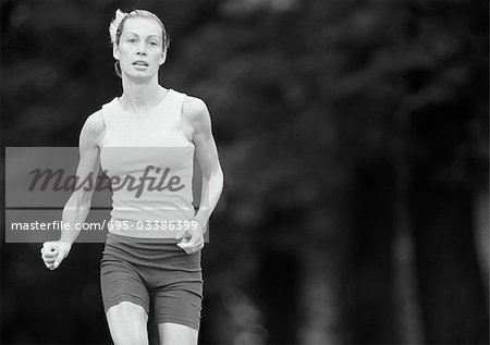 Woman in sports clothes running, three quarter length, b&w