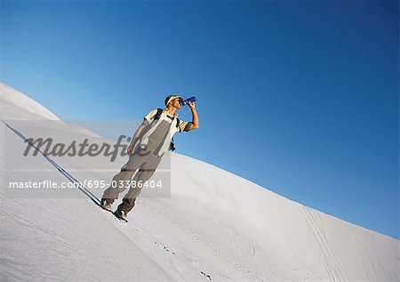 Hiker standing on dune, drinking