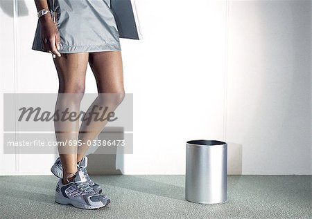 Woman wearing skirt and tennis shoes, low section