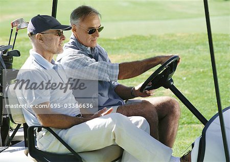 Two mature golfers in golf cart, close-up, side view