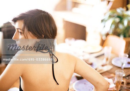Woman at table, wearing halter top, rear view