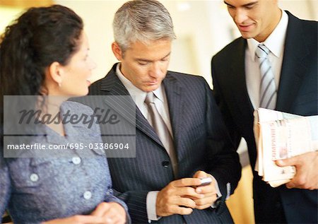 Businessmen and businesswoman, one holding cell phone