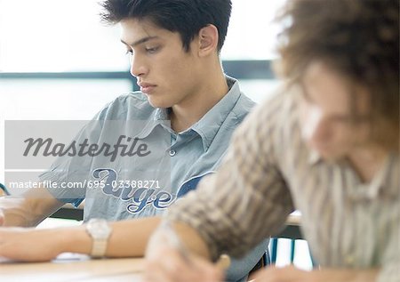 Two male students writing in class