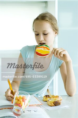 Girl doing homework and eating junk food