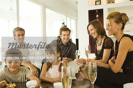 Four adults drinking champagne, watching children, smiling