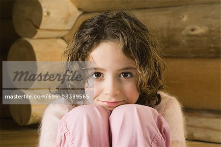 Girl sitting with head resting on knees, smiling at camera
