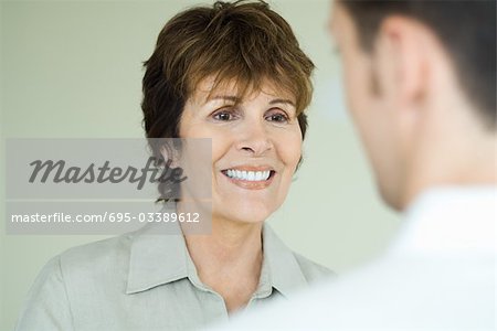 Woman smiling at man, viewed over man's shoulder