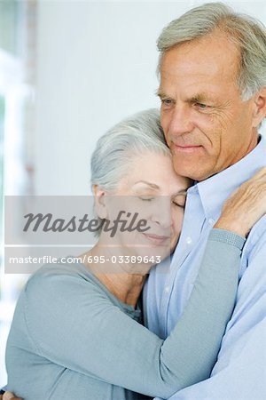 Mature couple embracing, woman's eyes closed, close-up
