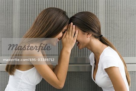 Twin sisters face to face, touching foreheads, side view