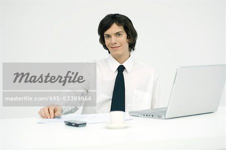 Young professional sitting at desk, smiling at camera