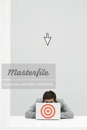 Computer cursor pointing at businessman hiding behind target