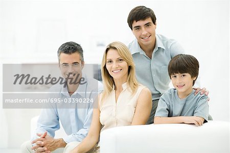 Family sitting together on couch, smiling, portrait