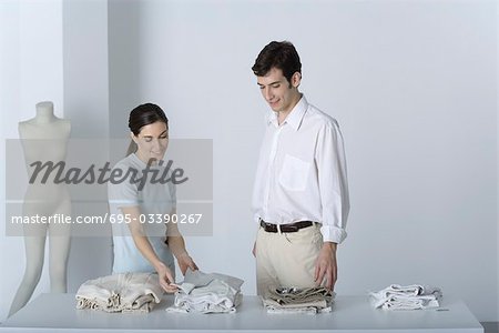 Saleswoman showing male customer a sweater, both smiling