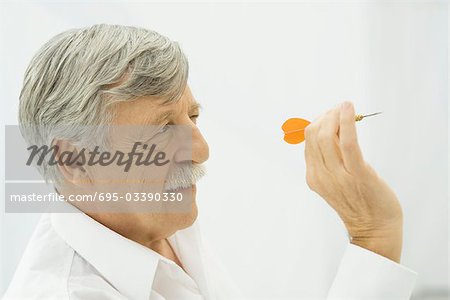 Senior man holding dart, aiming