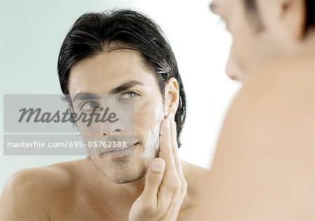 Man putting on shaving cream in mirror