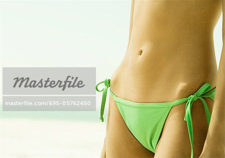 Woman wearing string bikini, close-up of abdomen - Stock Photo