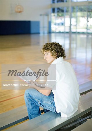 Teen boy reading book on bleachers