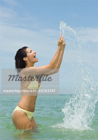 Woman standing in sea, splashing water with hands