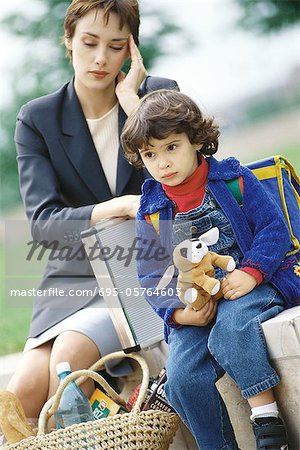 Businesswoman sitting with son, holding head