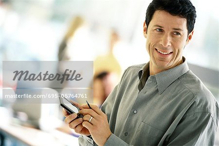 Man using electronic organizer, smiling