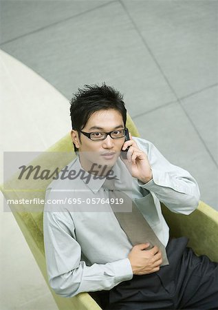 Businessman sitting in armchair, using cell phone