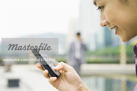 Businesswoman using messaging phone, smiling, close-up, side view