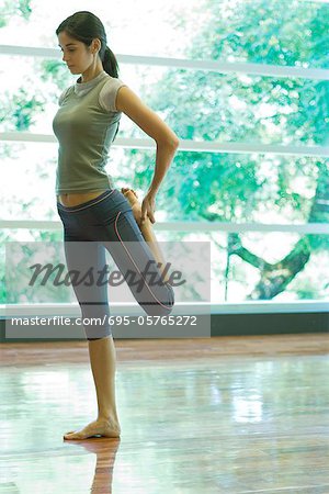 Young woman standing on one leg, stretching