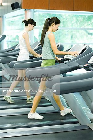 Two women walking on treadmills