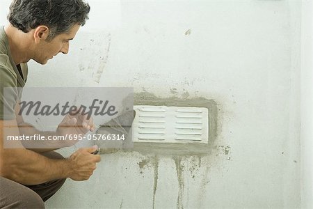 Man applying plaster around air vent