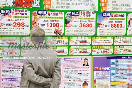 Man looking at ads on wall in Chinese, rear view