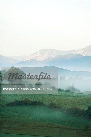 Rolling landscape with mist, mountains in the distance