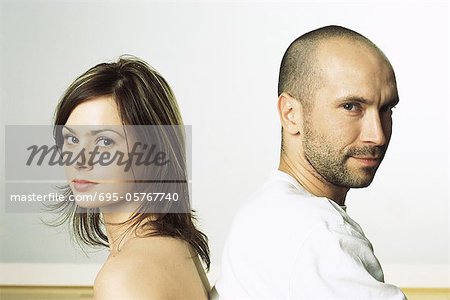 Couple back to back, both looking over shoulders at camera