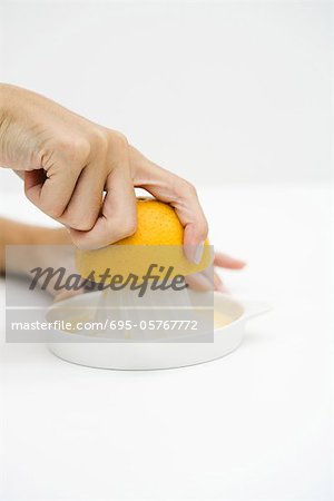 Woman juicing orange, cropped view, close-up