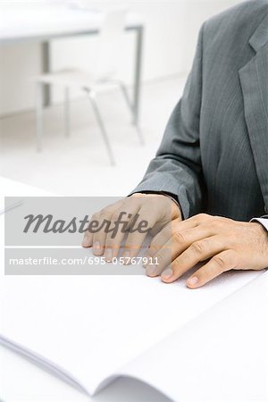 Professional man sitting at desk, reading Braille, cropped view of hands