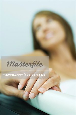 Woman in bathtub, holding man's hand, cropped view, focus on hands