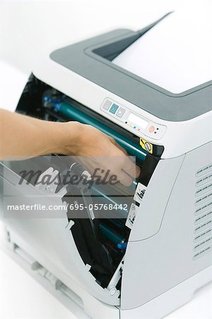 Person fixing paper jam in printer, cropped view