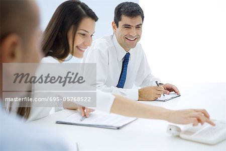 Professionals sitting at table, making conference call