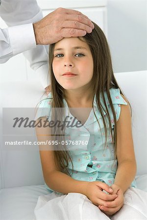 Doctor placing his hand on little girl's forehead, cropped view