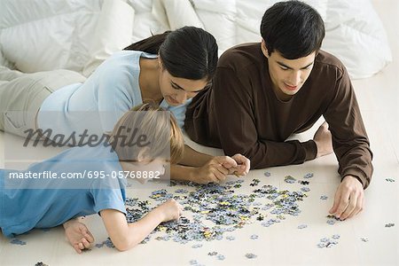 Family lying on floor, putting together jigsaw puzzle