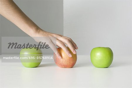 Three apples, hand selecting red apple