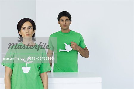Woman wearing tee-shirt with plant graphic, man holding watering can in background