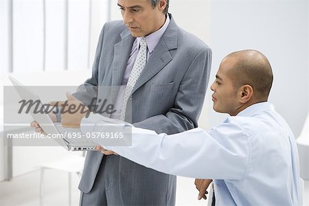 Two businessmen looking at laptop computer together in office