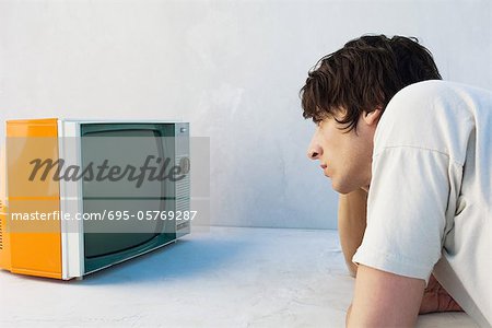 Young man leaning on elbow, watching television