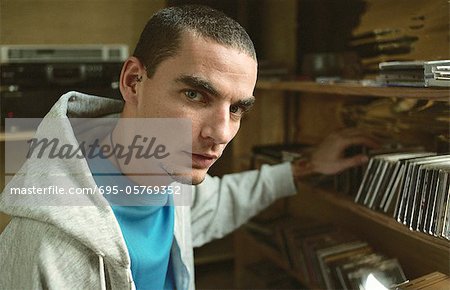 Young man selecting CD from collection on shelf