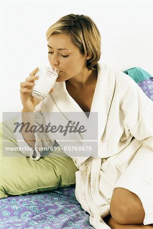 Woman in bathrobe drinking milk in bed