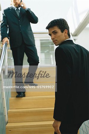 Businessman going up steps, looking over shoulder at camera