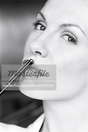 Woman touching lips with pen, glancing sideways at camera