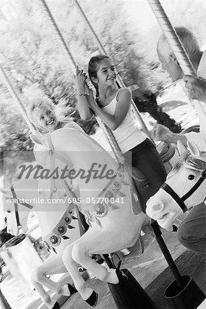 Girl riding carousel with her grandparents