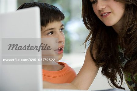 Sister and younger brother using laptop computer together