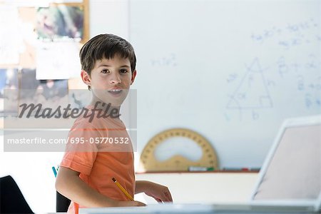 Elementary school student in classroom, looking over shoulder